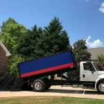 Truck Unloading Mulch on Driveway Surrounded by Trees
